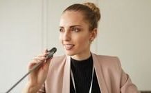 Overcoming Fear of Public Speaking: Expert Tips Woman standing on a stage, holding a microphone